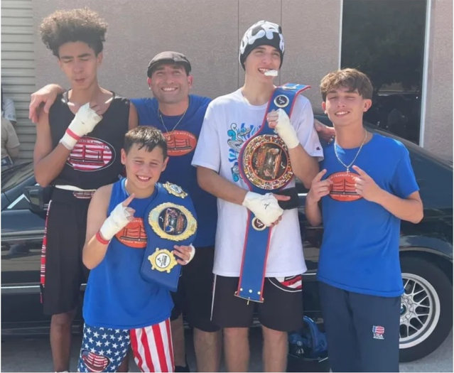 Coach and young boxers smiling with their boxing belts