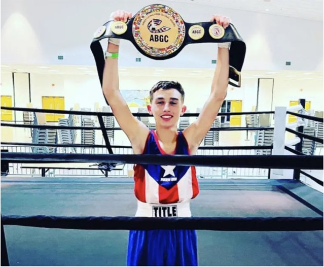 A young boxer raising a championship belt in the ring