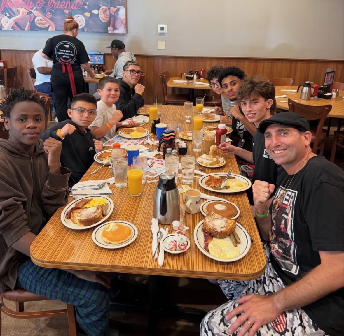 Coach Frankie and students sharing a team meal