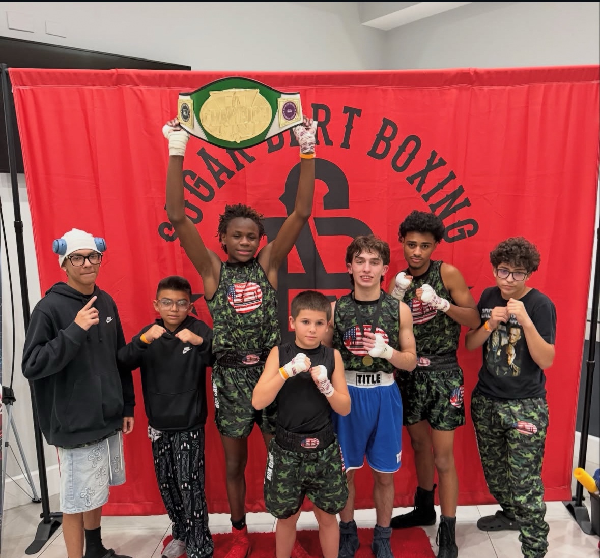 Young boxers celebrating with a championship belt